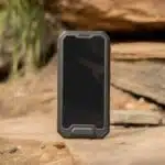 Um modelo de celular robusto sobre uma superfície rochosa ao ar livre, destacando sua resistência e proteção reforçada.